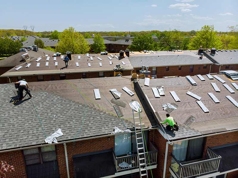 Enterprise Contracting, Inc workers installing new shingles on apartment buildings