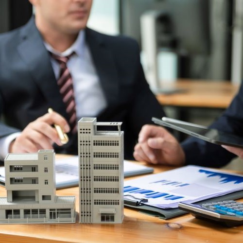 A building owner conversing a contract at a table with a small model building