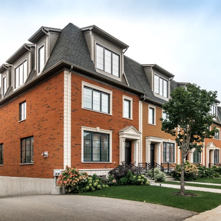 Low angle view of a brick property with a tree in the front