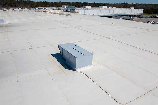 Top view of the flat, white commercial roof of a warehouse
