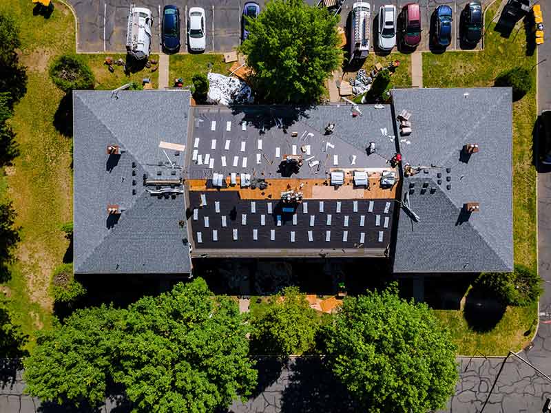 Top view of a large residential building getting new gray shingles installed