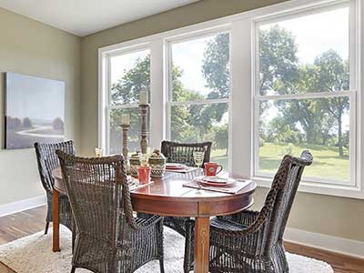Small dining room area with white Andersen windows behind a table and four chairs