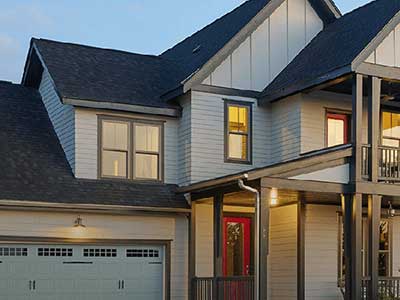 Residential, two-story home with white Mastic siding during dusk