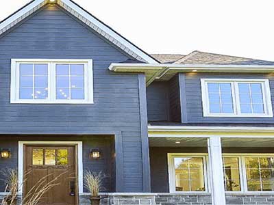 Front view of a large, two-story mid-class home with light blue Royal siding